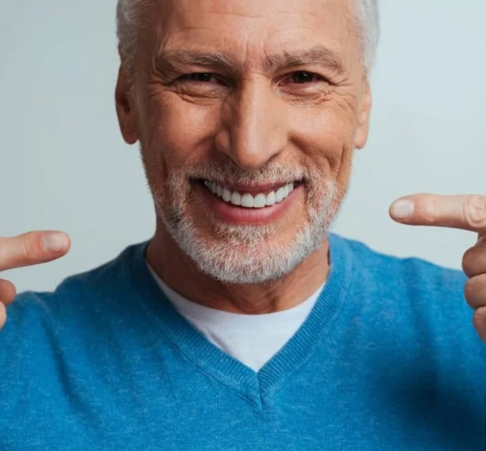Smiling older man pointing to his clean, healthy teeth