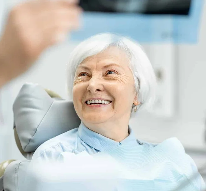 A smiling older woman at a dental visit, part of a healthy oral-care routine with Denta Guard